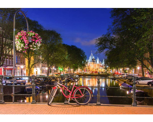Fotobehang met rode fiets op een Amsterdams bruggetje bij avond, omringd door verlichte grachtenpanden en stille grachten.