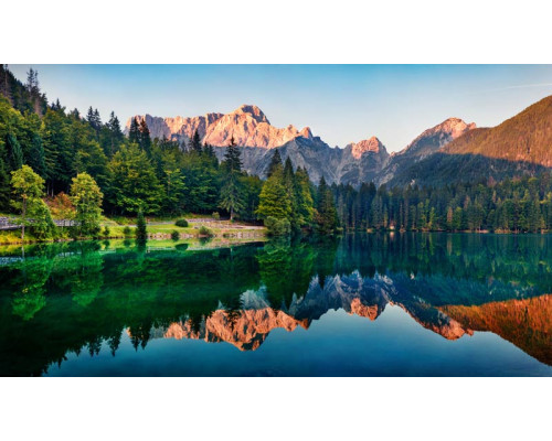 Reflecterend bergmeer met bossen en bergen die in het heldere water weerspiegelen, afgebeeld op een natuurgetrouw fotobehang.