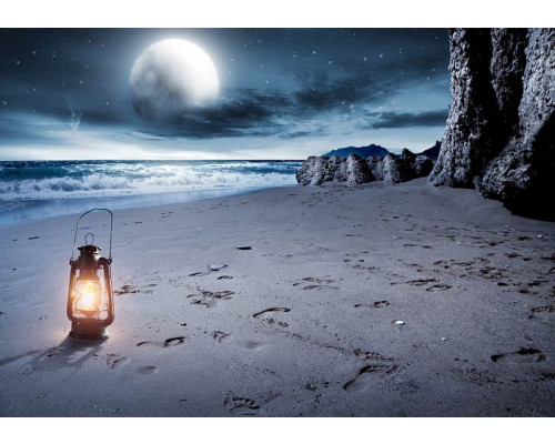Fotobehang van een volle maan boven een strand en zee, met een sfeervolle lantaarn.