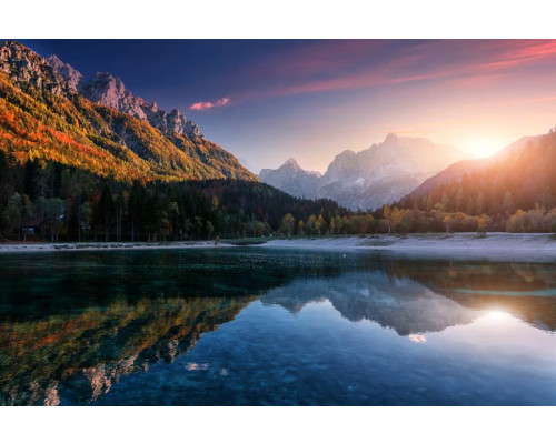 Zonsondergang aan een bergmeer, waar bergen en natuur het serene landschap vormen op dit fotobehang.