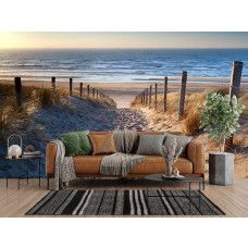 Fotobehang met een duinpad naar zee aan de muur van een lichte woonkamer met natuurlijke tinten.