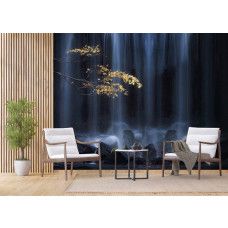 Een fotobehang van een herfsttak bij een waterval met rotsen en gouden tinten in een woonkamer met vliesbehang.