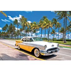 Fotobehang met een Geel-witte oldtimer aan een zonnige boulevard met palmbomen in Miami.