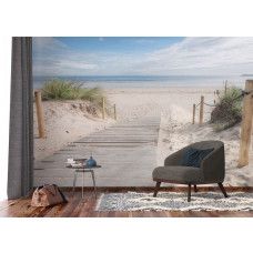 en fotobehang met een sfeervol houten pad naar het strand in de woonkamer, waar het houten vlonderpad en de omliggende duinen een rustgevende kustsfeer creëren.
