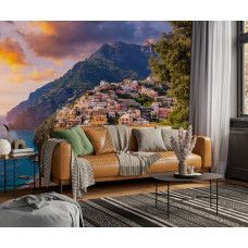 Fotobehang Positano bij zonsondergang met uitzicht over zee en bergdorp in een woonkamer.