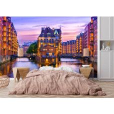 Fotobehang Speicherstadt Hamburg bij Avondlicht in de slaapkamer met warme verlichting en kalme waterreflecties.