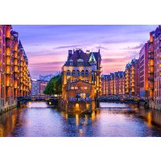 Fotobehang Speicherstadt Hamburg bij Avondlicht als productfoto met verlichte pakhuizen en reflecties in het water.
