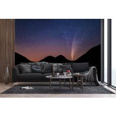 Een fotobehang van een sterrenhemel boven bergen en een meer in een woonkamer.