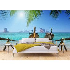 Een tropisch fotobehang met een zeezicht, kleurrijke bootjes en groene palmbladeren, perfect voor een kalme en exotische sfeer in een slaapkamer.