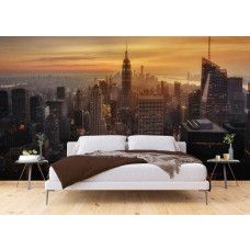 Een slaapkamer met een fotobehang met een magische zonsondergang boven de wolkenkrabbers van de New York skyline.