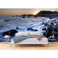 Een fotobehang van een zonsopgang bij het kiezelstrand van Forster Zee in een slaapkamer.
