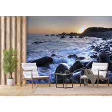 Een fotobehang van een zonsopgang bij het kiezelstrand van Forster Zee in een woonkamer.