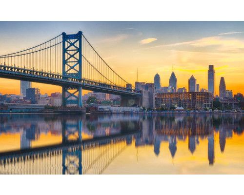 Ben Franklin Bridge in Philadelphia, met een reflectie in het water bij zonsondergang, afgebeeld op fotobehang.