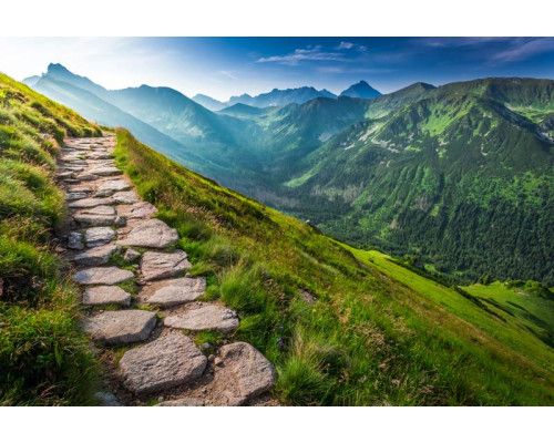 Fotobehang van een bergpad dat langs de bergtoppen slingert, met een weids uitzicht over het landschap.
