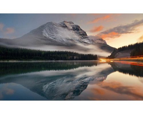 Fotobehang van een betoverend bergmeer omringd door bergen en bossen, dat een serene en rustige sfeer uitstraalt.