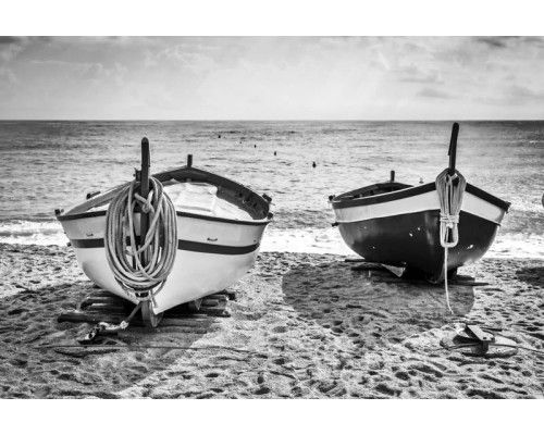 Fotobehang van kleine bootjes die aangemeerd liggen aan een zonnig strand, met een weids uitzicht over de zee.