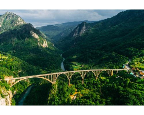 De Durdevica Tara-brug in Montenegro, omgeven door het Tara-gebergte en afgebeeld op een fotobehang met een landschap van bergen.