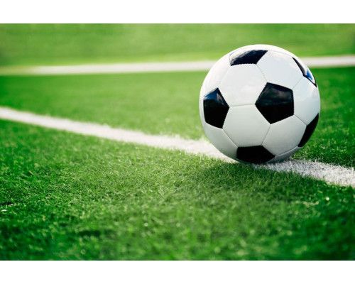 Fotobehang van een voetbal die op een grasveld ligt, klaar om in actie te komen tijdens een spannend moment in de wedstrijd.