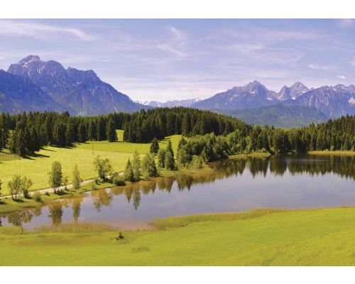Fotobehang van een meer in de bergen met een landschap van bos en bomen.