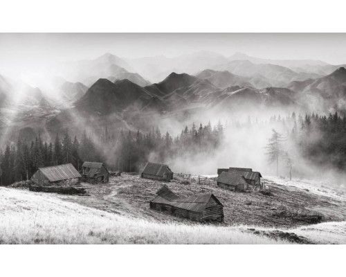 Fotobehang van een oude boerderij die verscholen ligt in de bergen, omgeven door dichte bossen en natuur.