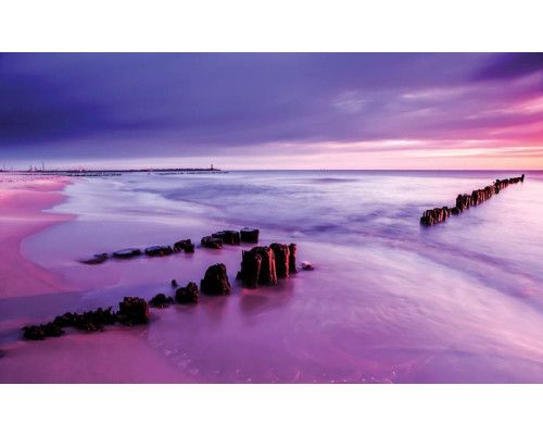 Fotobehang met een gekleurde horizon bij een zonsondergang aan zee.