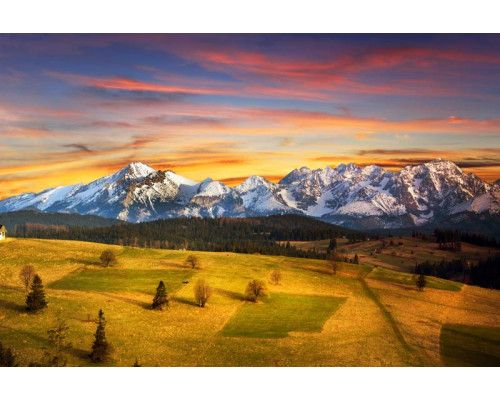 Het Tatra-gebergte in een zonsondergang, met bergen die schitteren in het avondlicht, weergegeven op een fotobehang.