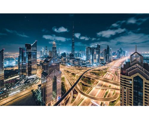 Verlichte stad in de nacht met snelwegen door het landschap.
