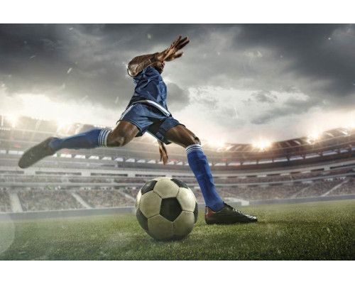 Fotobehang van een voetballer die actief speelt in een groot stadion, vastgelegd tijdens een cruciaal moment in de wedstrijd.