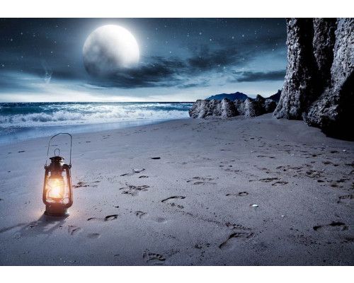 Fotobehang van een volle maan boven een strand en zee, met een sfeervolle lantaarn.