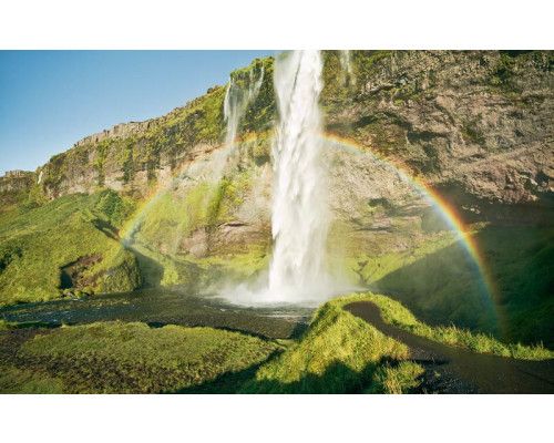 Seljalandsfoss waterval in IJsland met een regenboog in het landschap.