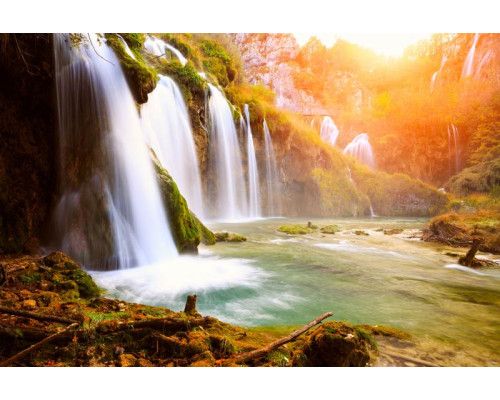 Fotobehang van een harmonieuze waterval die door een jungle stroomt, met weelderige groene vegetatie.