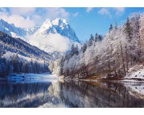 Fotobehang van een winterlandschap met besneeuwde bergen en een rustig meer dat het serene beeld compleet maakt.