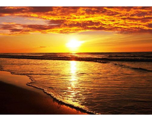 Fotobehang van een zonsondergang aan het strand boven zee.