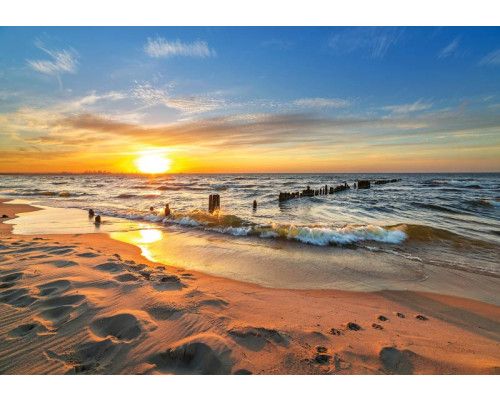 Fotobehang van een zonsondergang boven de zee, met een helder verlichte hemel en een serene strandomgeving.
