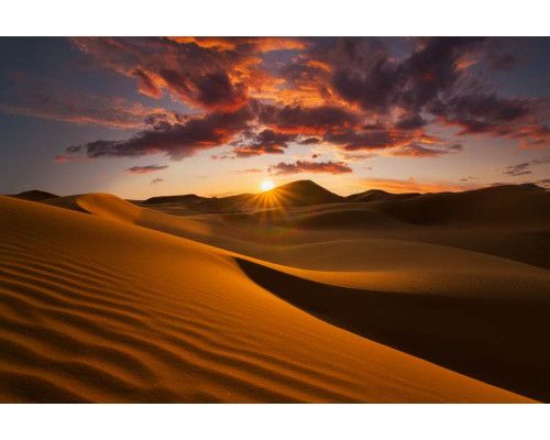 Fotobehang van een zonsondergang in de woestijn, waar de bergen worden verlicht door de laatste zonnestralen.