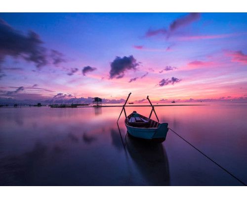 Fotobehang van een zonsondergang over een meer en zee, met landschap, boot en kano.