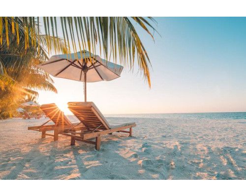 Fotobehang van een tropisch strand bij zonsondergang, met strandbedden die uitkijken op de rustige zee.