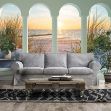 Een fotobehang met 3D-zicht op de duinen, strand en zee bij zonsondergang in een sfeervolle woonkamer.