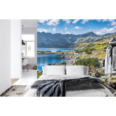 Een fotobehang met een kalm bergmeer en bergen, afgebeeld in een slaapkamer.