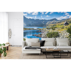 Een fotobehang met een serene bergmeer omgeven door hoge bergen, afgebeeld in een woonkamer.