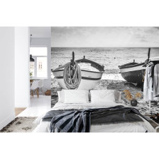Een fotobehang met een sfeervol strandbeeld met bootjes bij een kalme zee, geschikt voor een slaapkamer.