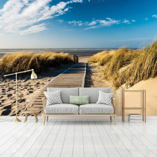 Een fotobehang van een strandlandschap met duinen en zee, dat een ontspannen sfeer geeft in een huiskamer.
