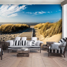 Een fotobehang met een kustlandschap van duinen en zee, passend voor een woonkamer.