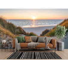 Fotobehang duinpad naar zee bij zonsondergang met begroeide duinen, een breed strand en warm zonlicht boven zee in de woonkamer.
