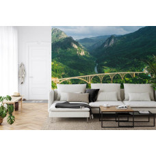 Een fotobehang met de Durdevica Tara-brug in Montenegro en omliggende bergen, weergegeven in een huiskamer.