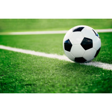 Fotobehang van een voetbal die op een grasveld ligt, klaar om in actie te komen tijdens een spannend moment in de wedstrijd.