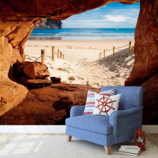 Een fotobehang met een strandpad gezien vanuit een grot in de huiskamer.