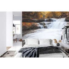 Een warm fotobehang van een herfstlandschap met een bosrijke waterval, ideaal voor een slaapkamer.