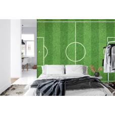 Een fotobehang met een uitgestrekt grasveld en een voetbal in een slaapkamer.
