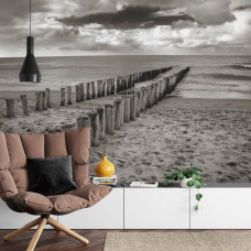 Een fotobehang met houten palen op een kalm strand, perfect voor een huiskamer.